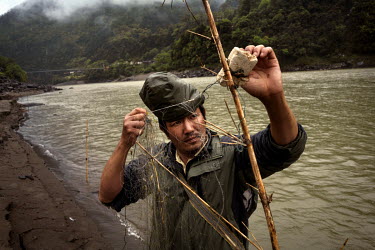 Li Zheng Xin, 36, a farmer who goes fishing whenever he can, sets a net to catch fish in the Nujiamg River in Chala Village.