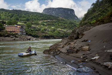 He Yong Cai, 50, an ethnic Naxi farmer who is also known as Acai, rows his inflatable boat on the Nujiang Riverin order to set out his fishing nets. He used to use a wooden boat but now uses the infla...