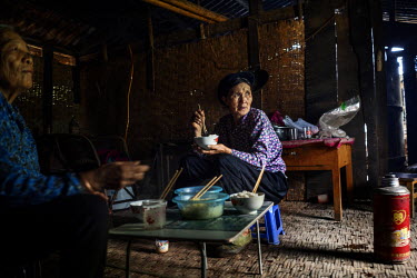 A Lisu woman eats a meal in her home in the Nujiang River valley.