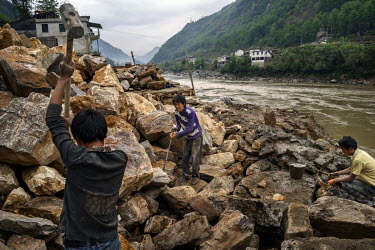 Local Lisu construction workers build the foundations of a ten story building on a bank of the Nujiang River. The workers are paid 100 Yuan (11.25 GBP) per day and live in basic tents with their famil...
