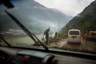 People watch as workers try to clear a blockage on the road that runs alongside the Nujiang River.