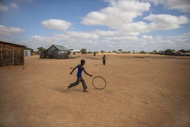 A young Somali refugee plays with a bicycle wheel in Dadaab refugee camp.