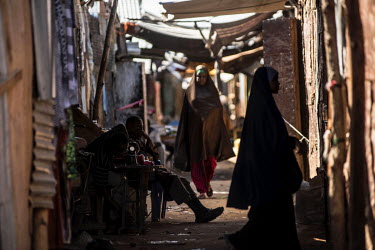 Women walk past a tailor in a commercial neighbourhood of Dadaab refugee camp.