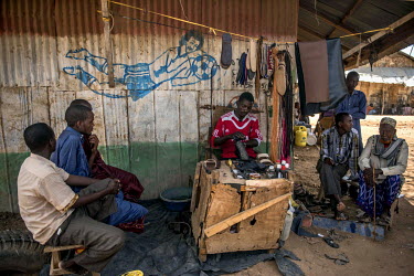 A cobbler works beneath a mural of a football player in Dadaab refugee camp.