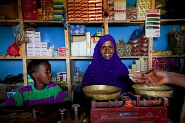 A woman and a boy standing behind a pair of scales on the counter of a small shop.  A devastating drought is causing the worst food crisis to hit Ethiopia in 30 years, putting millions of people at ri...