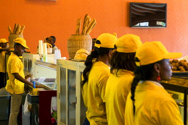 Bakery staff serve from behind a counter at an outlet for Pain Victoire. They have a modern industrial bakery with the capacity to produce six million baguettes per day. The Lebanese owned facility su...
