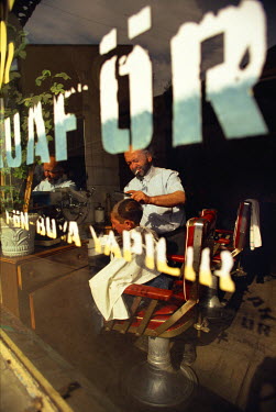 A boys has his hair cut in a barber's shop.