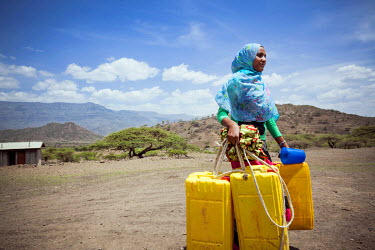 19 year old Kadija carrying her three jerry cans to a new water facility near her cafe. Before this new supply began Kadija would have to walk for hours to fetch clean water. She explains, 'I used to...