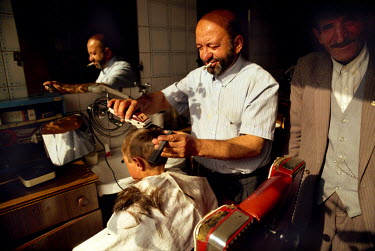 A boy has his head shaved in a barber's shop.