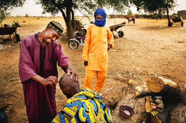A village hairdresser shaves a man's head on the roadside between Diffa and Zinder.