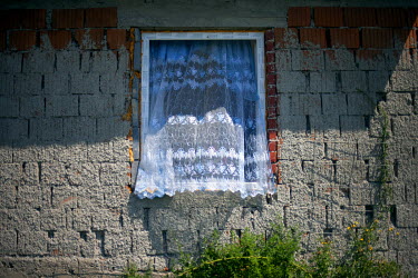 A newly installed window with a net curtain and an unfinished facade in the village of Rankovce where a micro loans project for the local Roma community enables families to build their own low-cost br...