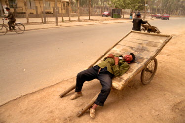 An ethnic Uighur man taking a nap on his hand-cart.