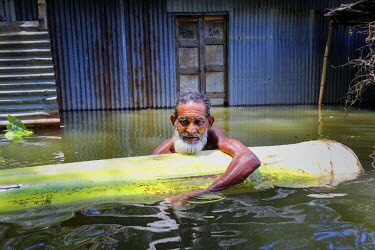 Moin Miah (75) floats in flood water, holding onto a banana palm stem, while looking for his lost belongings that have been washed awayfrom his house.  At least 820,000 people have been affected by fl...
