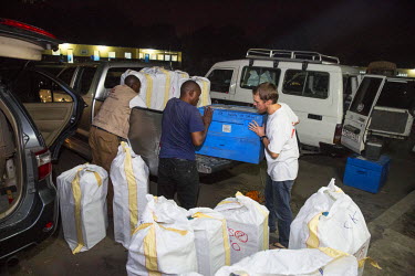 Medecins Sans Frontieres (MSF) staff load vehicles on the night before the start of a massive yellow fever vaccination campaign.