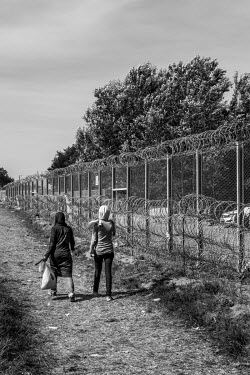 Refugee woman walk past the razor wire at the border between Horgos, Serbia and Roszke, Hungary which remains closed after Hungarian authorities closed the crossing.