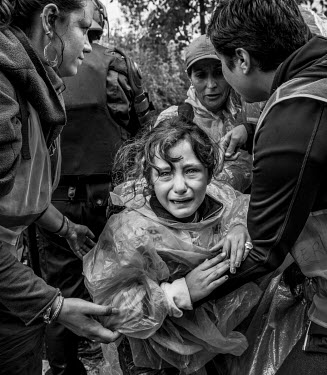 A crying child is held by volunteers during scenes of turmoil at the train station as thousands of refugees wait to get on a train or a bus.