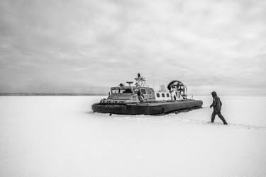 An estonian border guard heading towards a hovercraft to patrol the lake.