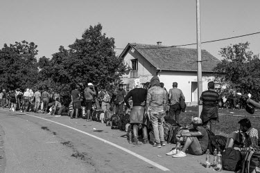 A group of refugees wait for a rare bus at the roadside.
