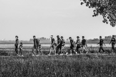 A group of refugees walk to an area in the village where they'll be picked up by buses taking them to various destinations as they seek to travel onto Western Europe.