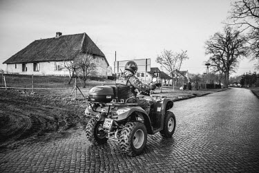 A border guard drives a quad bike through the village on the main street which runs to the Russian border.
