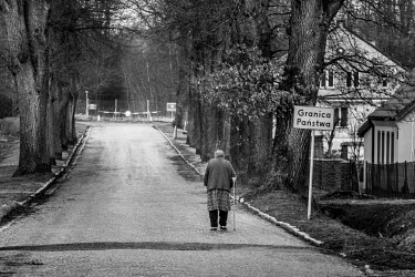 An elderly woman walks along the village's main street towards the Russian border.