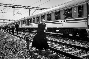 A refugee woman and her son cross the rail tracks at a station.