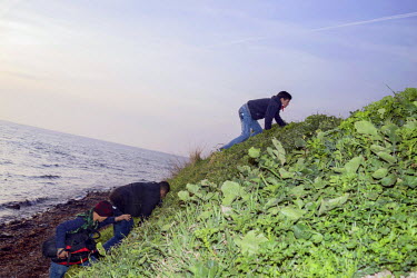 Refugees that have just landed scramble up the hillside to make their way towards the centre of the Island.