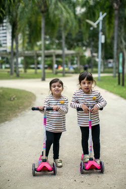 Twins three-year-olds Manuela and Mariana ride their scooters on a path in Peninsula, an exclusive planned community complex of high-end, high-rise condominiums.   Breakneck development has brought pr...