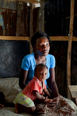 Christela Louis with one year old Niderson inside her makeshift corrugated iron home in Grand Ravine.