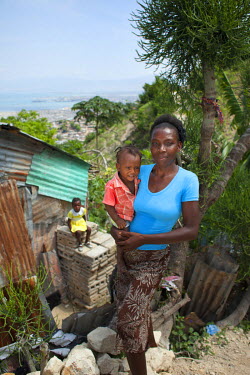 Christela Louis holding her son next to her home in Grand Ravine. She will be working in a new bakery which is due to open soon. She received training from Concern.