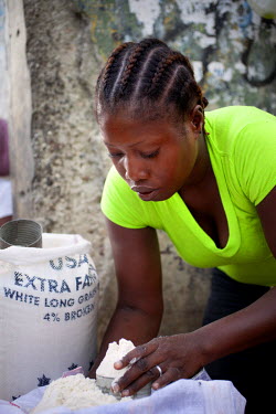 Wilmise Saintilma measures out flour in her small business she runs in a market in Carrefour.