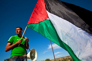 A man holds a Palestinian flag at the weekly demonstration, held by Palestinian activists and their suppoters in Bilin (Bal'in), protesting at the construction of the Israeli Separation Wall, that cau...