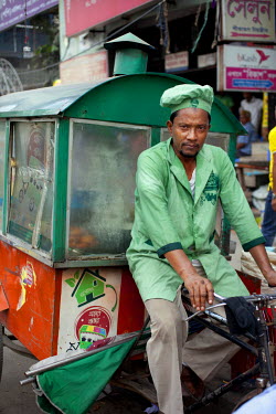 Ariful Islam Zafar, known as Zafar, with the mobile food cart he uses to cook and sell snacks on the streets of Dhaka, Bangladesh.