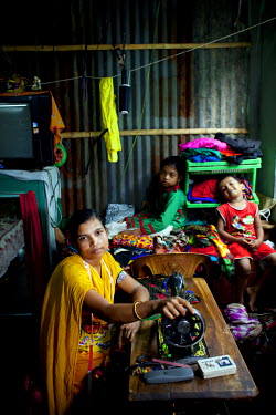 Moyna at her home in Jhilpaar, with her daughter Sumaiya (10) and son Shafin (five), and the sewing machine she uses to run her tailoring business.