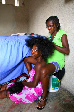 A woman takes out her friend's extensions before restyling her hair.