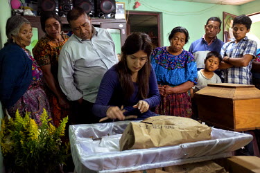 Forensic anthropologist Yeni De Leon arranges the skeletal remains of Simon Buc Tamat inside a coffin while family members watch, including his son Joaquin Buc (green shirt) and widow Fidelia Sahuach...