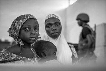 A mother and her sick children wait for a consultation with one of two doctors who have made it to the town with the aid of the military. Soldiers provide security in a territory where the surrounding...