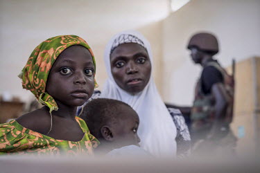 A mother and her sick children wait for a consultation with one of two doctors who have made it to the town with the aid of the military. Soldiers provide security in a territory where the surrounding...