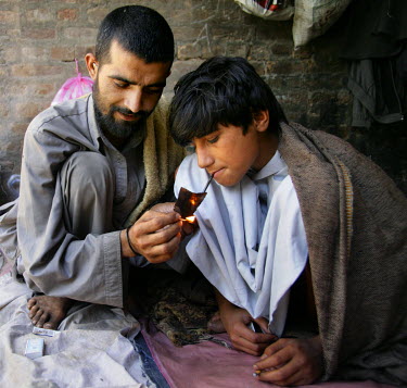 A man assists as a child smokes heroin.  Beneath a bridge in the city young people (some minors) and adults live together. It is claimed that the adults introduce the children to drugs so that they ca...