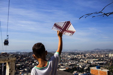 A youth launches a kite from the Palmeira cable car station in Complexo do Alemao in the North Zone.