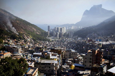 High rise condominiums in the wealthy neighbourhood of Sao Conrado, centre, and the sweeping landscape of Rocinha, the largest single favela in Rio de Janeiro. To the left smoke rises from a fire as r...