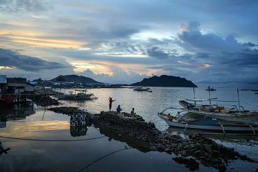 Children fish with hand lines at dusk from the docks of a fishing community of Quezon. Most of the people living here have a member of family who works as a fisherman and ply their trade in national a...