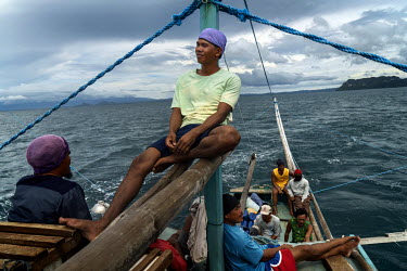 Crew members relax and fish with landlines for their dinner and fish they can sell to suppliment their pay, on the 'Ninay', a basnig fishing boat, as they head out for a night fishing for scad and sar...