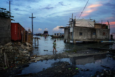 A pregnant woman walks through the dirty water at one of the markets in the Navotas Fish Port, the largest fish port in the Philippines. The markets at Navotas Fish Port trade in fish and other seafoo...
