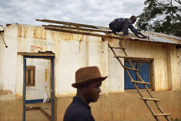A man repares the ceiling of a school in Muhuya. According to some witnesses the roof of the school was burned during fighting between ethnic Twa pygmies and Bantu Luba. The conflict in Katanga, a vas...