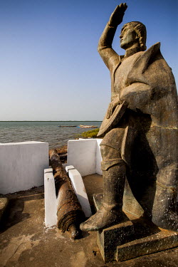 A bronze statue of the Portuguese explorer Diogo Cao which stands inside the slave-trader's fort of Cacheu. In the background is the River Cacheu.