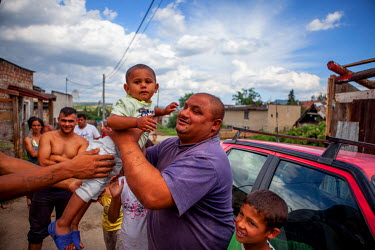 A man holds a child in the Roma settlement of Ostrovany while other villagers look on.
