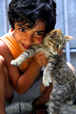 A child plays with a cat in a city suburb.
