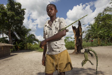In the small village of Lieki on the Lomami river, a boy carries his latest catch, a lizard he will eat.