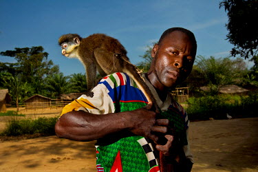 In Yafira, a village on the Lomami river, a man poses with a pet monkey on his shoulder.